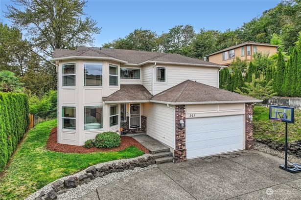 This two-story home features a modern exterior with clean lines and a welcoming front entrance. Large, bay-style windows on the front add a sophisticated touch, allowing for ample natural light inside while enhancing the home&#39;s curb appeal. The exterior is a blend of light siding and brick accents, adding a charming contrast and classic style. A spacious driveway leads to a two-car garage, perfect for convenience and storage. The landscaped front yard is neatly designed with shrubs and a stone-lined garden bed. A basketball hoop in the driveway adds a playful, family-friendly element. The house is nestled in a tranquil, tree-lined neighborhood, offering privacy and scenic surroundings.