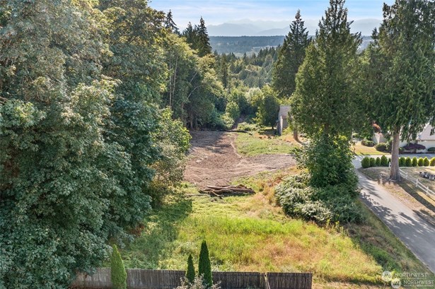 View from over the East end of the parcel looking west. Approximately 1/4 of the property has been cleared in anticipation of development. The grassy area in the foreground of the photo is an easement for the primary and reserve area of the adjacent property&#39;s septic system.