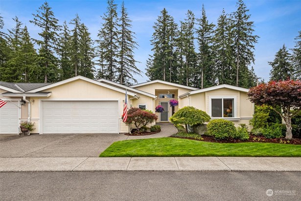 The front view of this rambler style condo home showcases the single story design with a welcoming covered front porch and well maintained yard.