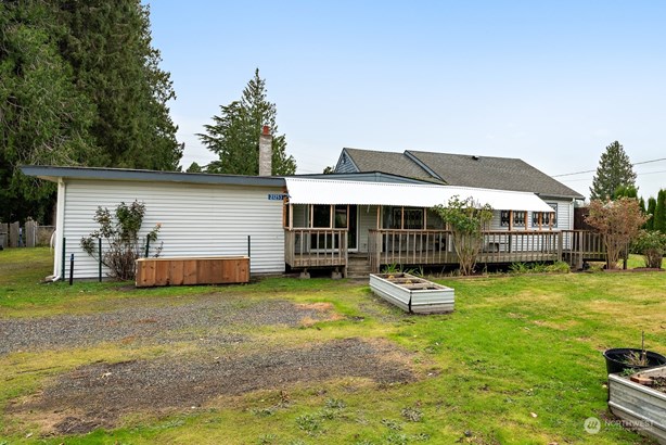 Covered front porch with extended canopy provides protection from sun and rain.