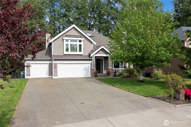 Immaculately maintained exterior with mature landscaping, a spacious three-car garage, and covered front porch create an inviting first impression.