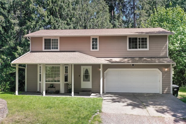 Front view of home, gorgeous woods behind, covered front porch and 2-car garage plus driveway parking for you and your guests.