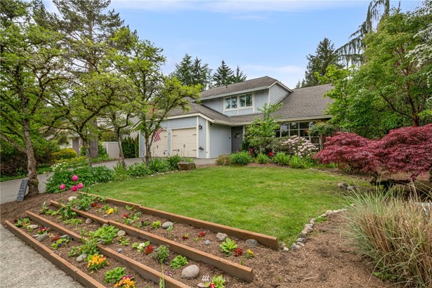 Classic two-story home with gridded windows, tiered front flowerbeds, mature landscaping awaits you here!
