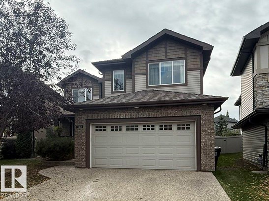 View of front of home featuring driveway, brick siding, a shingled roof, and a garage