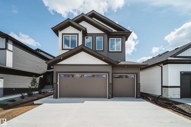 Craftsman-style home with driveway, stone siding, and an attached garage