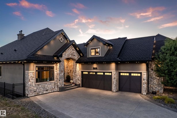 View of front of home featuring stone siding, driveway, and stucco siding